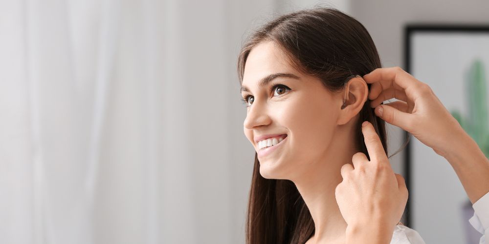 ragazza sorridente indossa apparecchio acustico