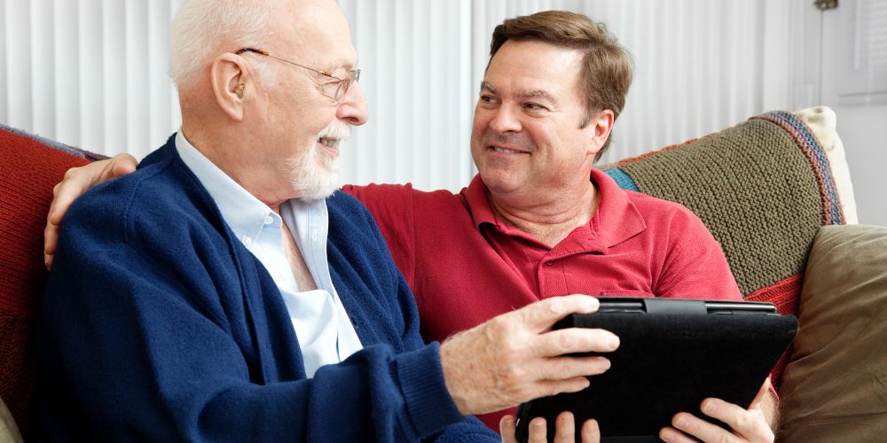 adulto aiuta anziano con un tablet
